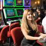 92207066-portrait-of-a-cute-caucasian-young-woman-playing-in-a-slot-machine-at-a-casino-and-smiling